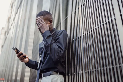 Une personne inquiète regarde l'écran de son smartphone pendant un appel.