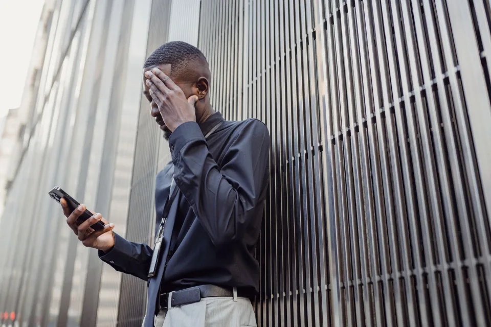 Une personne inquiète regarde l'écran de son smartphone pendant un appel.