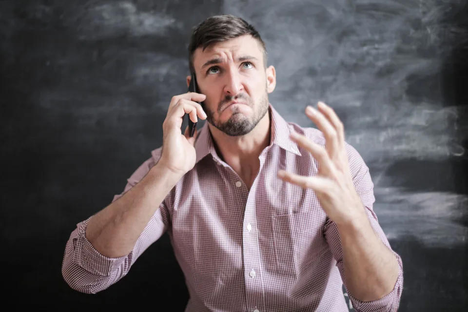 Une personne agacée regarde l'écran de son smartphone affichant un appel indésirable.