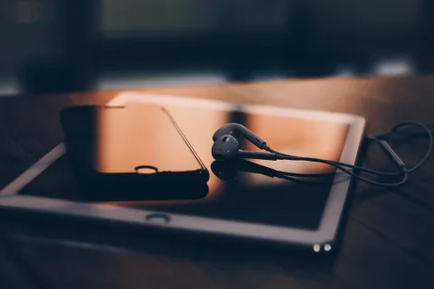 Un smartphone posé sur une table en bois à côté d'un casque audio de couleur noire.