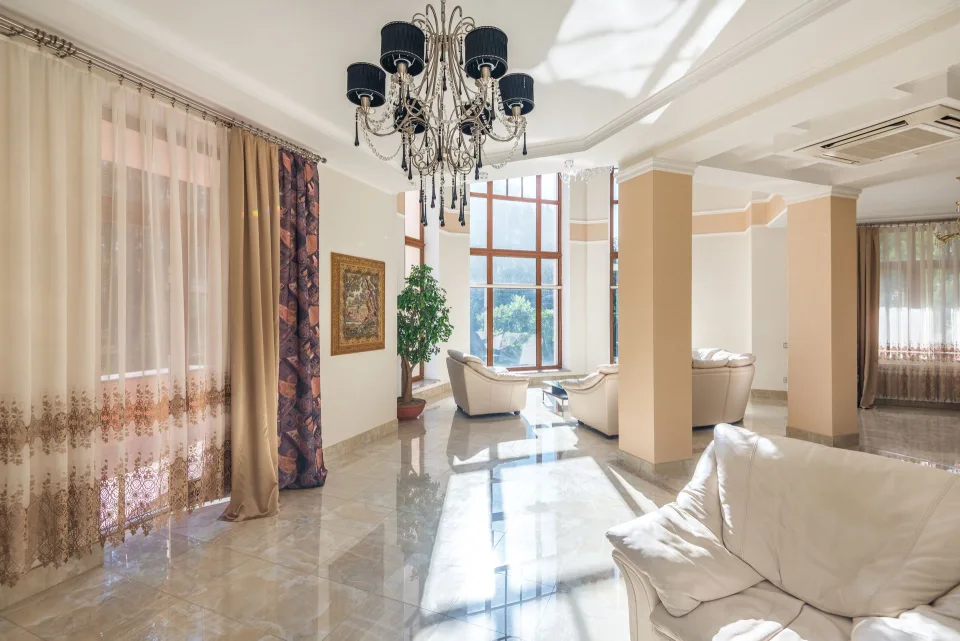 Un salon moderne avec un canapé gris, des coussins en velours vert et des accessoires en laiton doré.