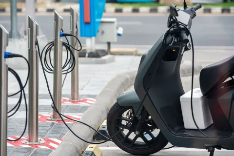 Une petite voiture électrique blanche en train de recharger sur une borne en ville.