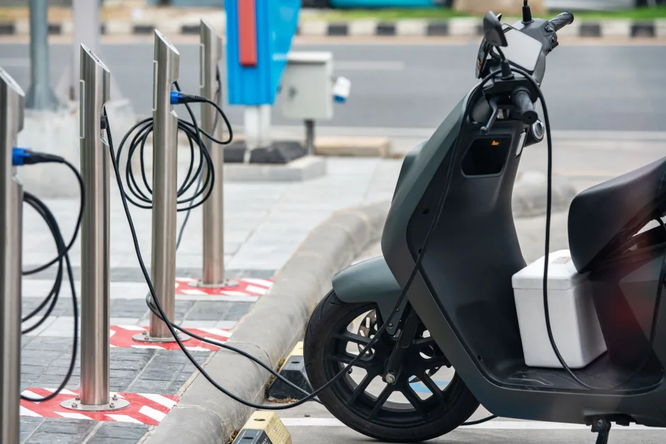 Une petite voiture électrique blanche en train de recharger sur une borne en ville.