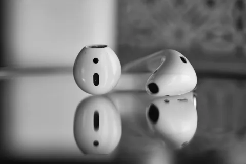 Une personne nettoie délicatement un écouteur intra-auriculaire blanc sans fil avec un petit pinceau.