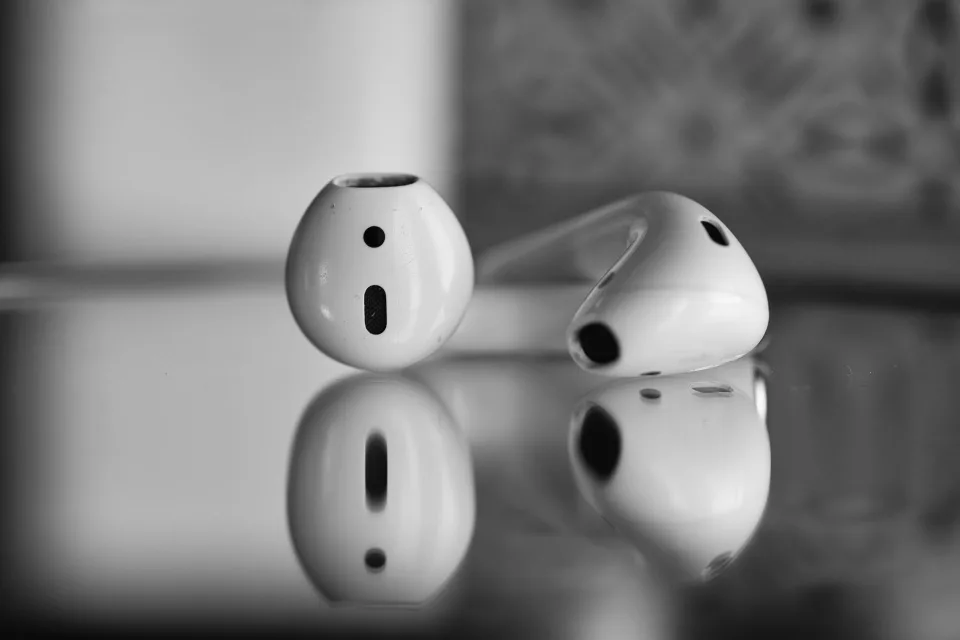 Une personne nettoie délicatement un écouteur intra-auriculaire blanc sans fil avec un petit pinceau.