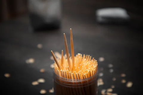 Une personne utilise délicatement un cure-dent en bois pour retirer la poussière du port de charge d'un smartphone.