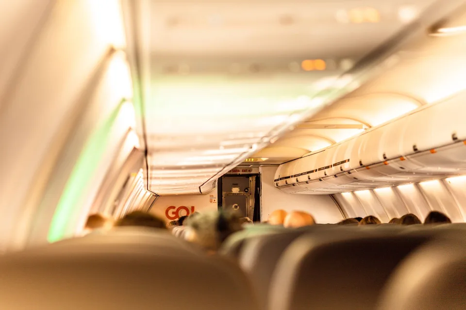 Un sac à dos souple gris parfaitement rangé glissé sous le siège d'un avion de ligne
