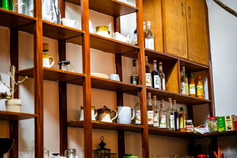 Des étagères en bois clair parfaitement ordonnées dans une cuisine lumineuse avec de la vaisselle en grès et des bocaux.