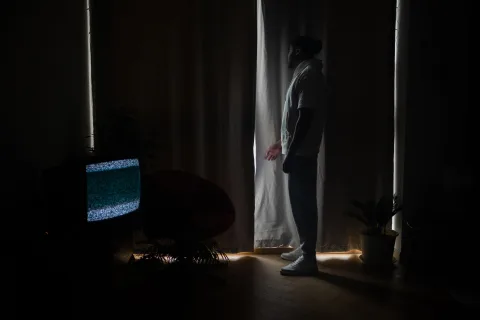 Un écran de télévision dans le noir diffusant une silhouette mystérieuse sous une lumière verte.