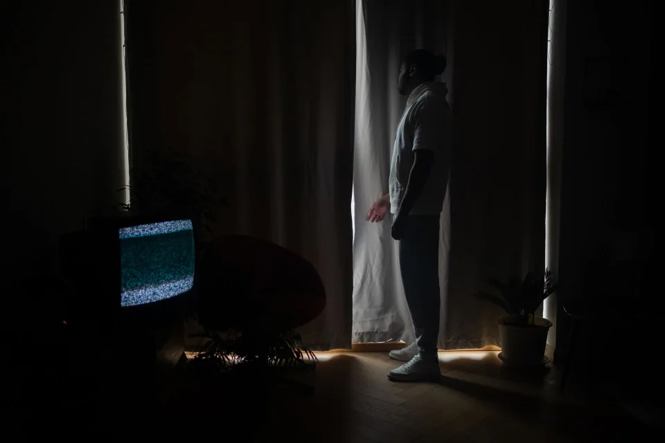 Un écran de télévision dans le noir diffusant une silhouette mystérieuse sous une lumière verte.