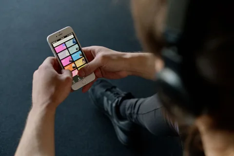 Une personne sélectionne des chansons sur l'application Spotify affichée sur l'écran de son smartphone dans une pièce sombre.