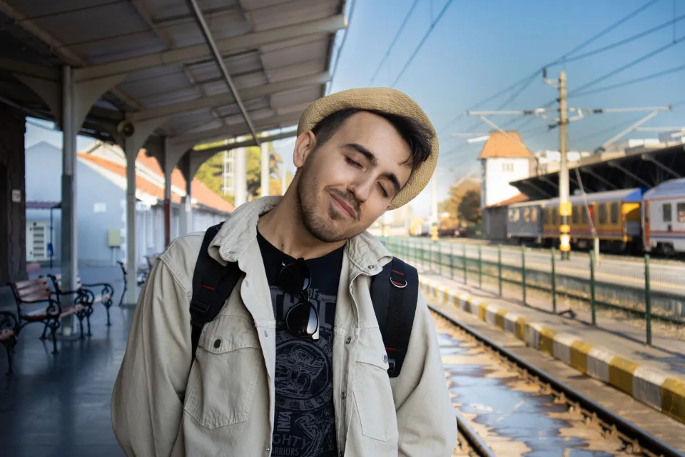 Une jeune voyageuse avec un sac à dos consulte un plan dans une gare européenne ensoleillée.