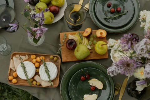 Une table en bois en plein air avec du fromage local, du cidre artisanal et du pain frais dans un verger normand.