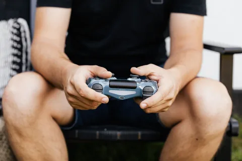 Une personne tient une manette de console devant un écran affichant des graphiques de prix.