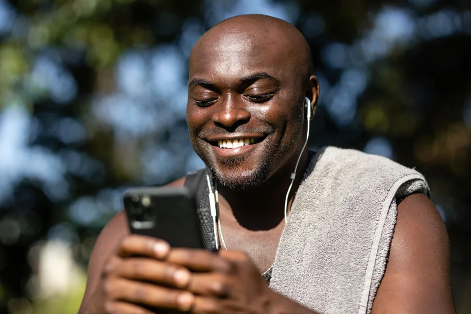 Une personne de profil portant un casque audio sans fil de haute qualité et tenant son smartphone.