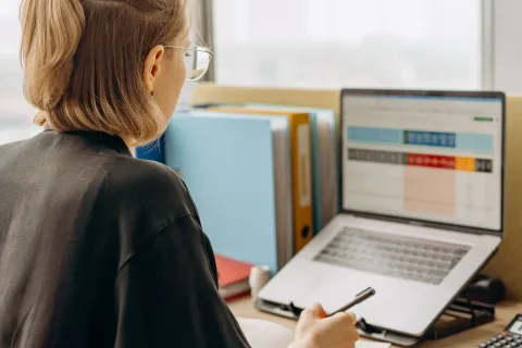 Une personne assise à son bureau examine un document complexe affiché sur l'écran de son ordinateur portable.
