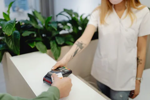 Une personne présente sa carte européenne d'assurance maladie et sa carte de crédit à l'accueil d'une clinique moderne.