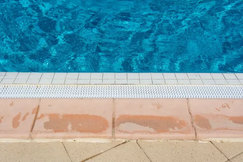 Une personne passe une serpillière humide sur un carrelage frais et propre dans un salon ensoleillé.