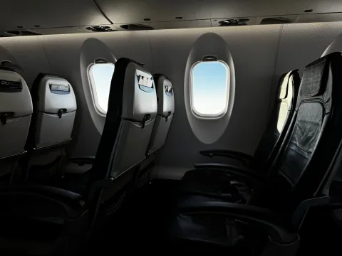 Un passager glisse un sac à dos souple sous le siège devant lui dans un avion.