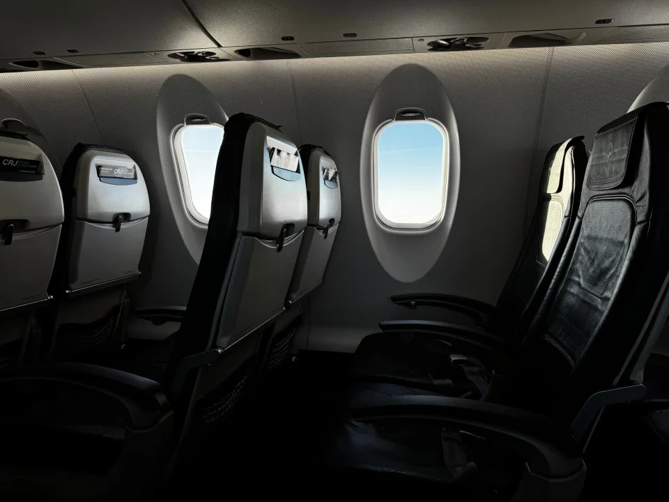 Un passager glisse un sac à dos souple sous le siège devant lui dans un avion.