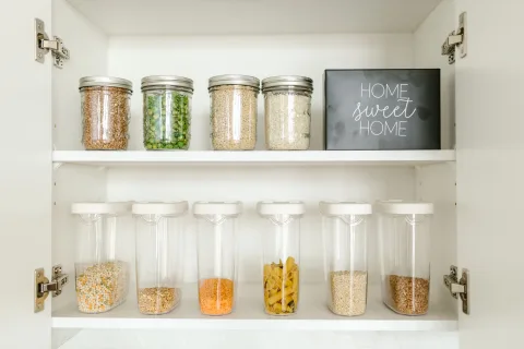 Des récipients en verre transparent contenant des légumes coupés et des céréales bien rangés dans un réfrigérateur propre.