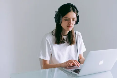Une personne concentrée travaillant sur son ordinateur portable avec un casque audio réducteur de bruit.