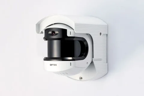 Une caméra de surveillance blanche fixée sur la façade d'une maison individuelle.