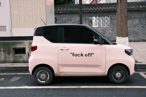 Une petite voiture sans permis électrique garée dans une rue urbaine moderne sous le soleil.