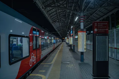 Une personne plie son vélo noir compact sur le quai d'une gare moderne en attendant le train.