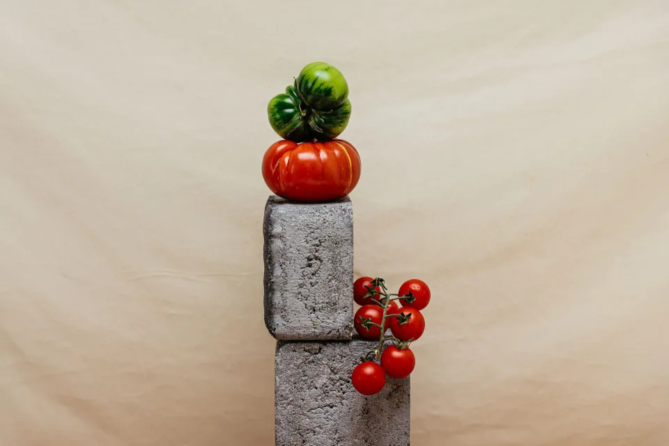Des tomates vertes disposées sur du papier journal à côté d'une banane mûre.