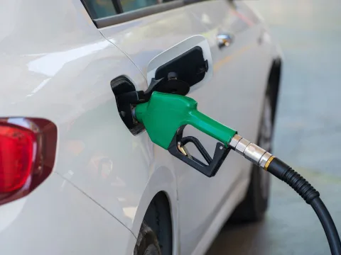 Une personne insère le pistolet bleu de superéthanol E85 dans le réservoir d'une voiture blanche