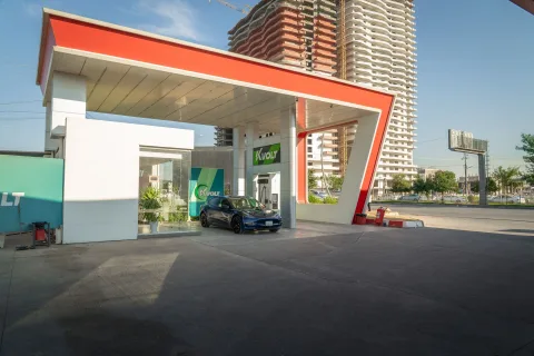 Une borne de recharge pour voiture électrique en milieu urbain avec un smartphone affichant une application de transport.