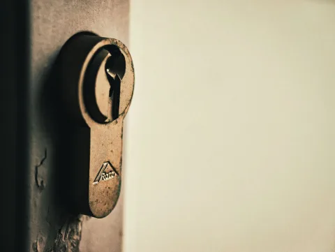 Une clé de maison insérée dans la serrure d'une porte d'entrée vue de l'intérieur de nuit.