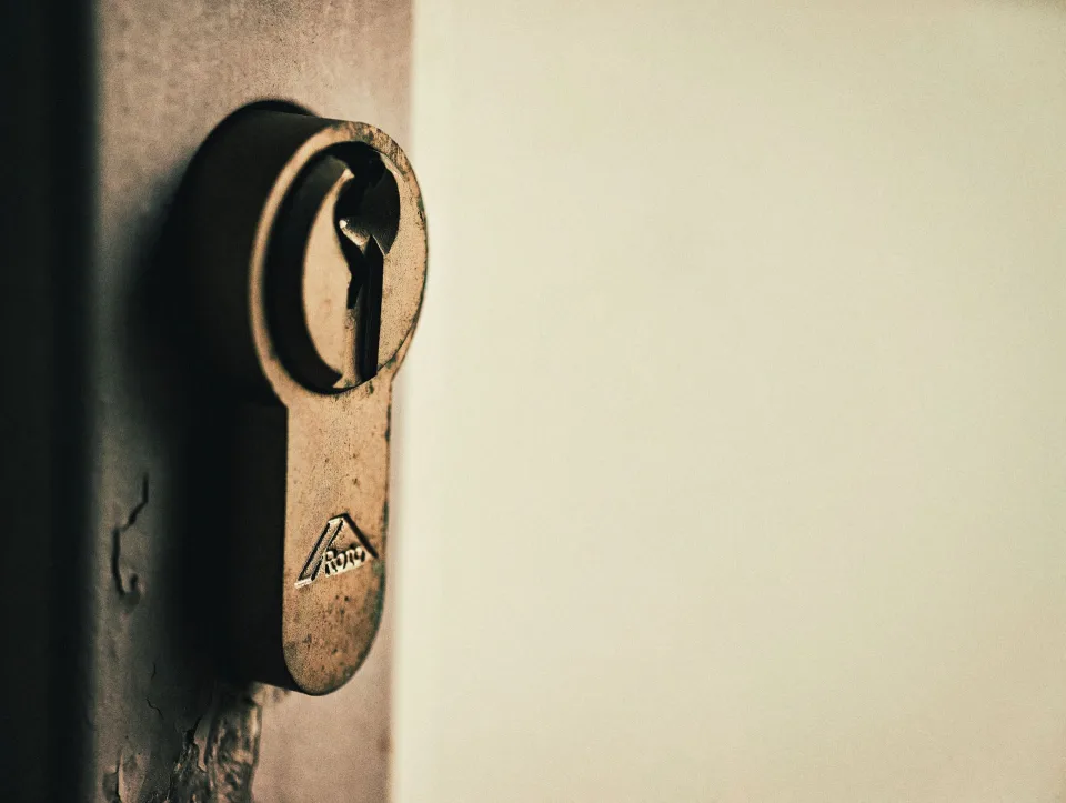Une clé de maison insérée dans la serrure d'une porte d'entrée vue de l'intérieur de nuit.
