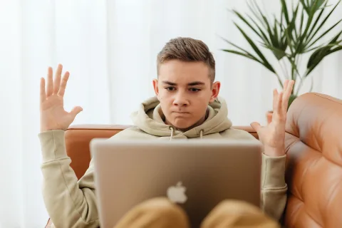 Une personne déçue devant son ordinateur portable affichant une icône de chargement interminable.