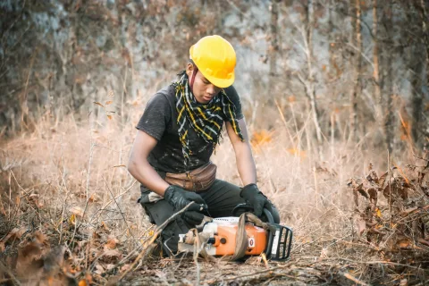 Un propriétaire forestier débroussaille un terrain sec près de sa maison.