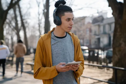 Personne marchant dans la rue avec des écouteurs et un smartphone rangé dans la poche