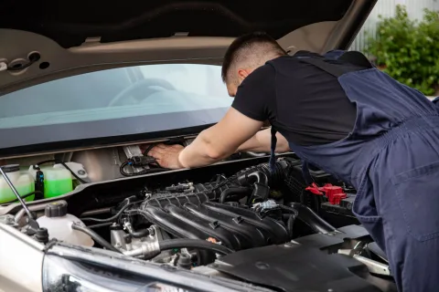 Une personne remplace le filtre à air d'un moteur de voiture dans son garage.