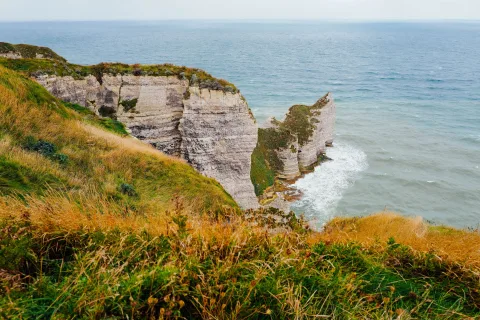 Une falaise verdoyante surplombant une mer calme sous le soleil de septembre en France