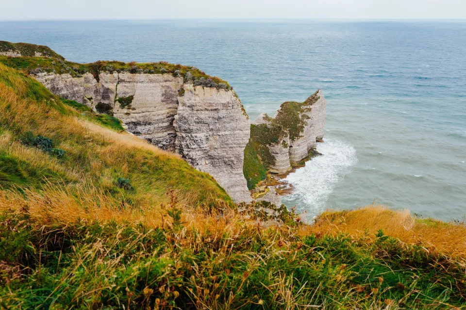 Une falaise verdoyante surplombant une mer calme sous le soleil de septembre en France