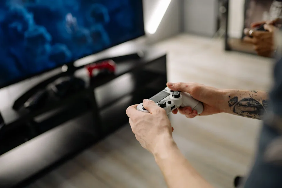 Manettes de jeux vidéo posées sur une table de salon devant un écran