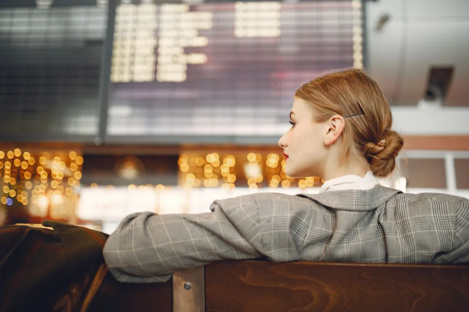 Un voyageur dépité regarde un panneau d'affichage des vols en retard dans un aéroport.