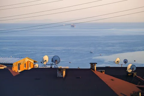 Une antenne satellite blanche installée sur le toit d'une maison de campagne sous un ciel bleu.