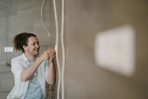 Un électricien insère un micromodule connecté derrière un interrupteur mural classique démonté.