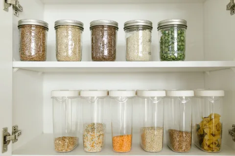 Une cuisine bien organisée avec des bocaux en verre étiquetés dans un placard propre.