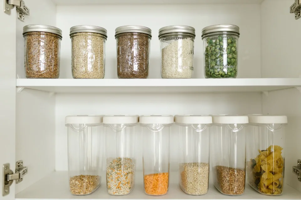 Une cuisine bien organisée avec des bocaux en verre étiquetés dans un placard propre.
