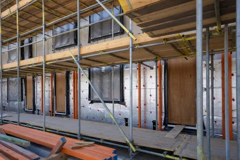 Installation de panneaux rigides de fibre de bois sous une toiture en bois.