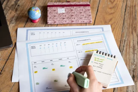 Un agenda ouvert sur un bureau en bois avec des plages horaires colorées dessinées au feutre