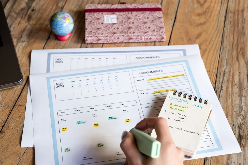 Un agenda ouvert sur un bureau en bois avec des plages horaires colorées dessinées au feutre