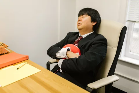 Un homme d'affaires assoupi sur son siège de bureau inclinable avec un masque de sommeil